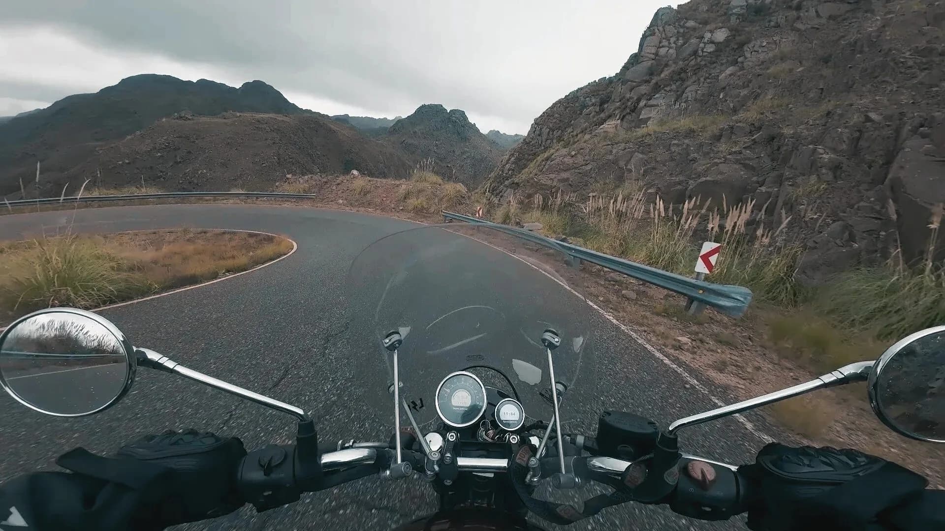 Vista desde el manubrio de la moto encarando una curva de montaña, cámara de acción a bordo
